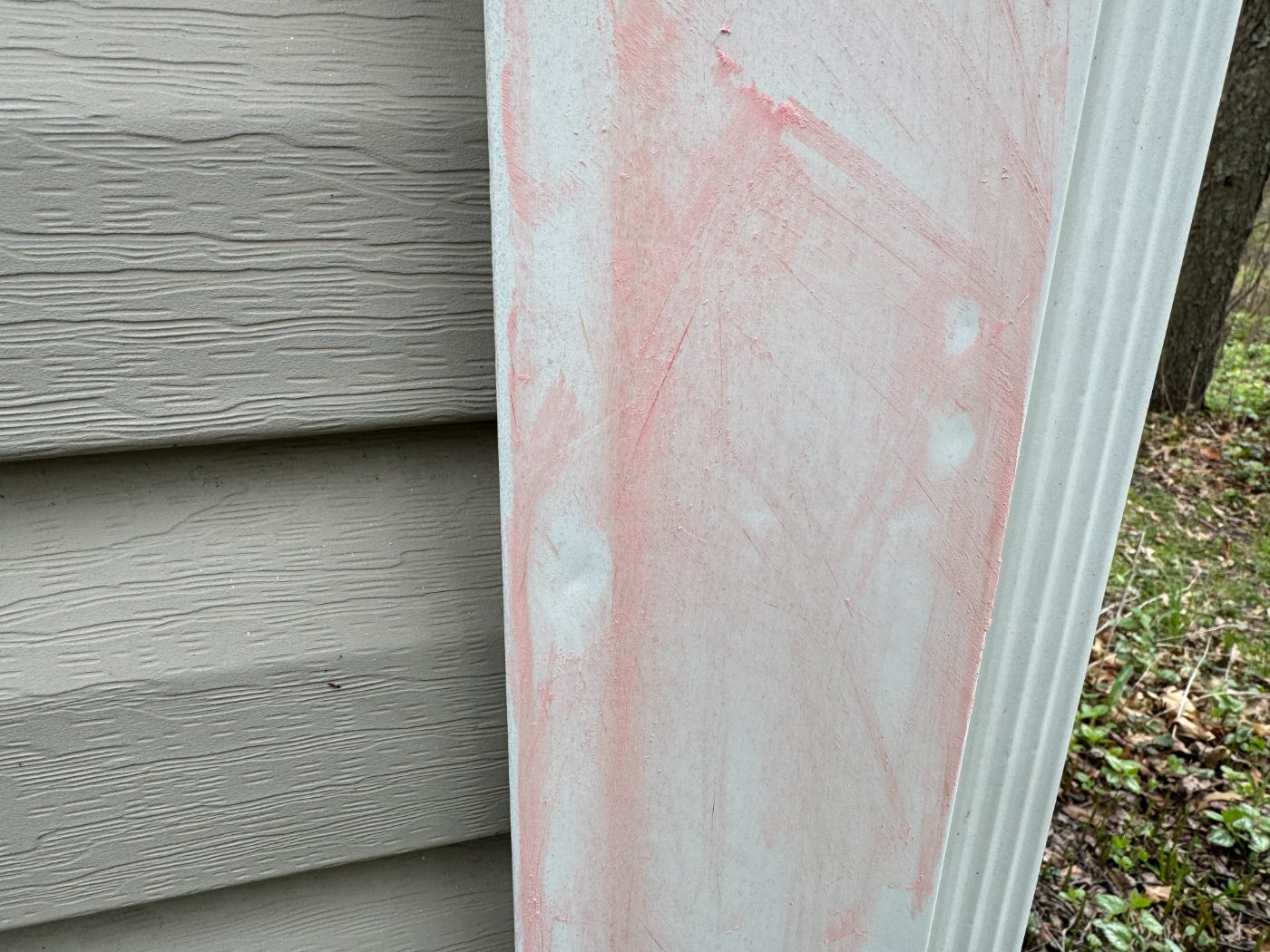Chalk-marked hail impacts on painted exterior trim beside lap siding