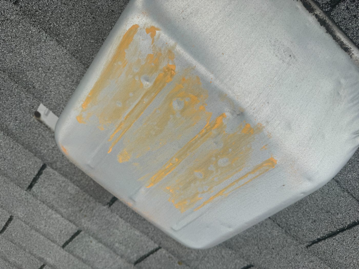 Chalk-highlighted hail dents on a white metal roof vent cap