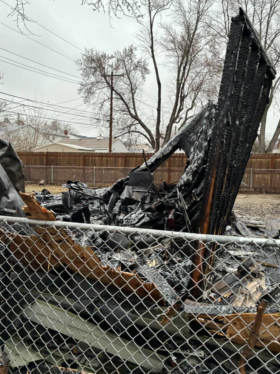Detached garage burned to the slab, one charred gable wall still standing above collapsed roof debris