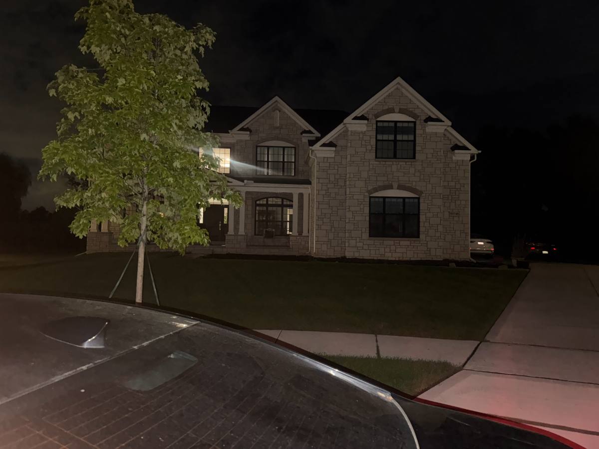 A client's two-story stone home at night with the lights on, fully restored